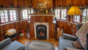 Una habitación acogedora con chimenea, paredes de madera y dos sofás.