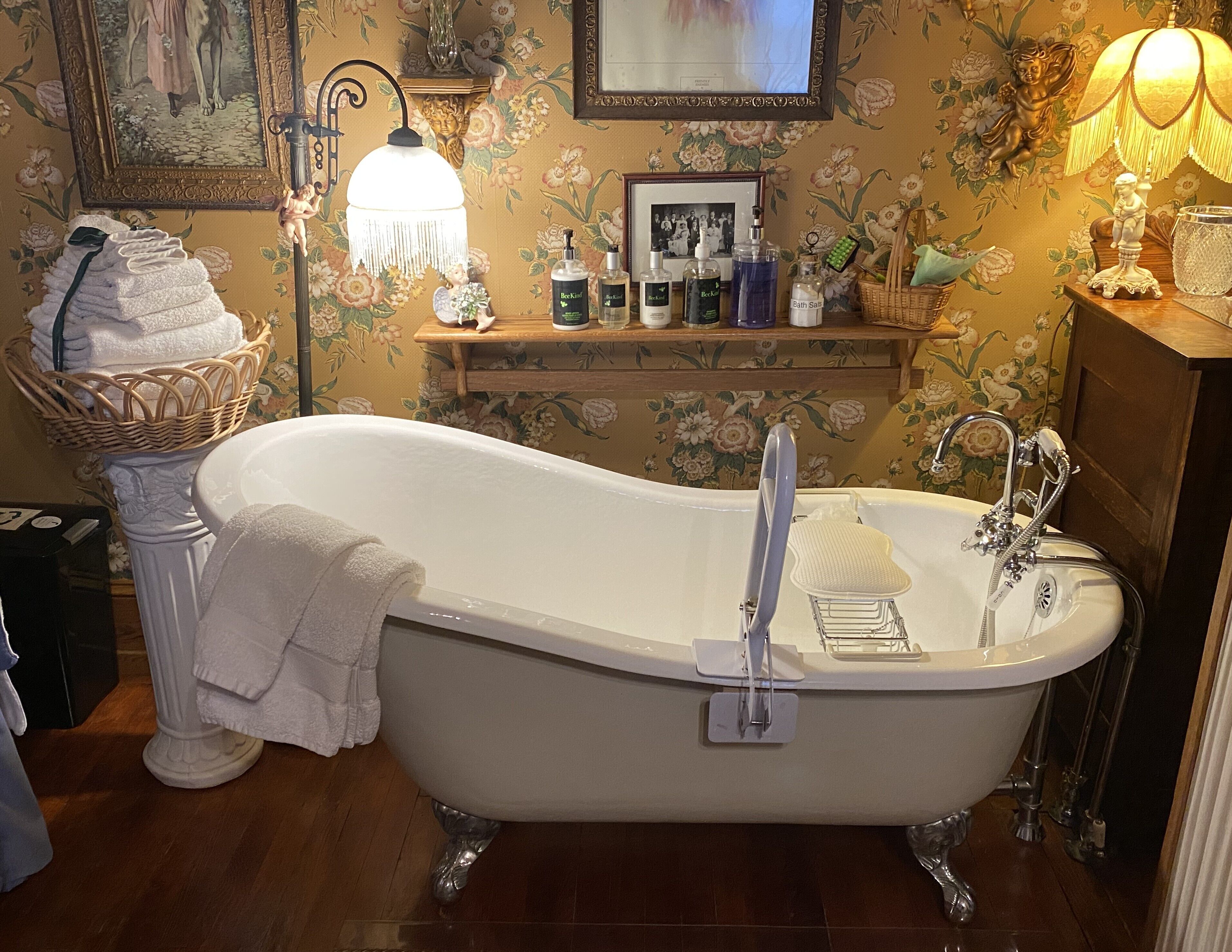 A classic clawfoot bathtub with a wooden vanity and a shelf with toiletries.