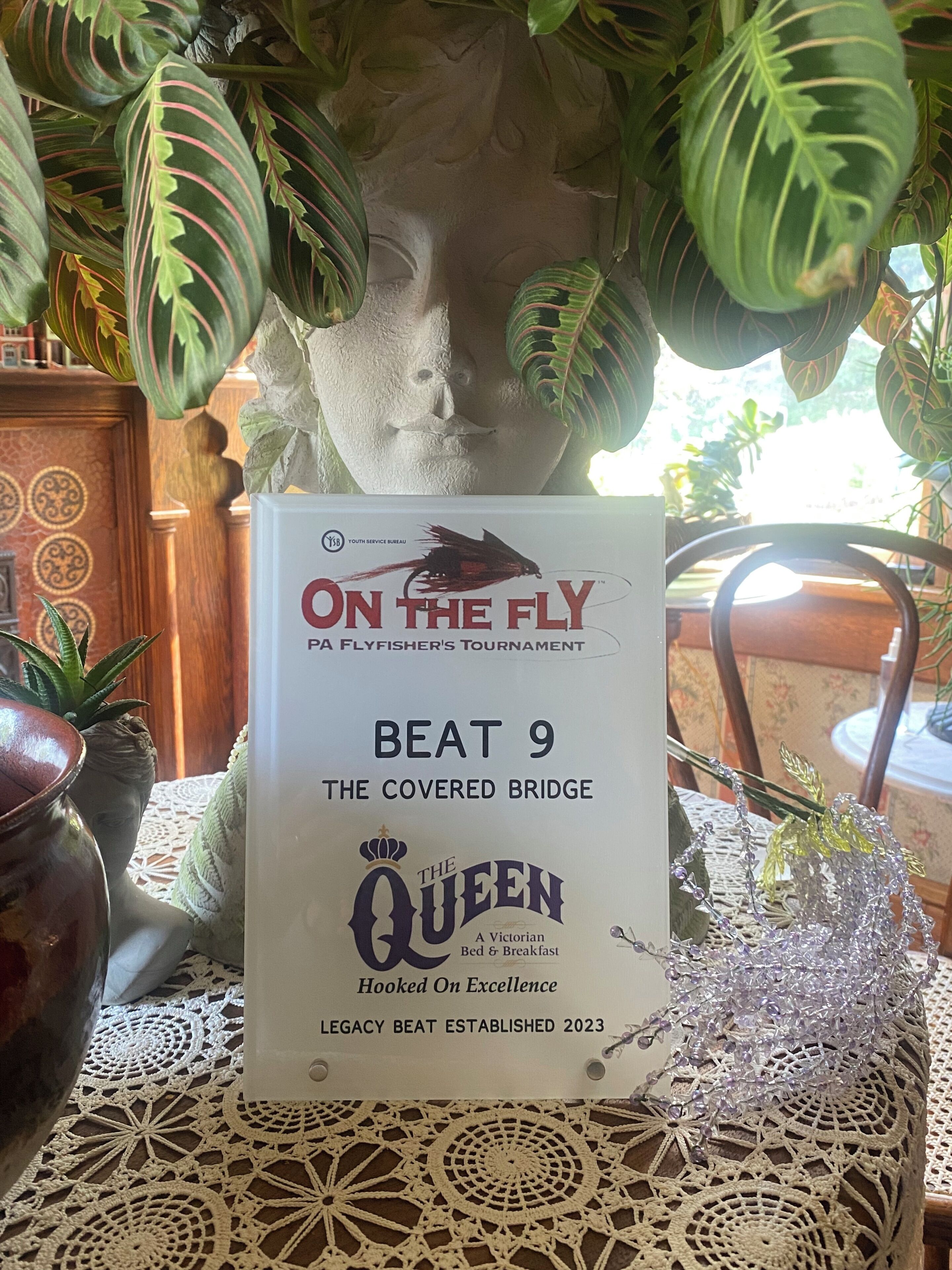 Una mesa con un cartel anunciando el evento 'On the Fly' y 'Beat 9 The Covered Bridge'.