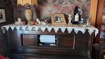 A piano with a lace tablecloth, a lamp, and decorative items on top.
