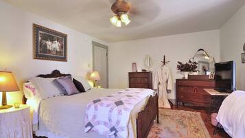 A bedroom with a bed, bedside lamps, a dresser, a mirror, and a television.