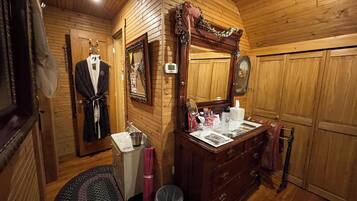 L’intérieur d’un chalet en bois, avec une coiffeuse en bois, un miroir, un peignoir et un petit lavabo.