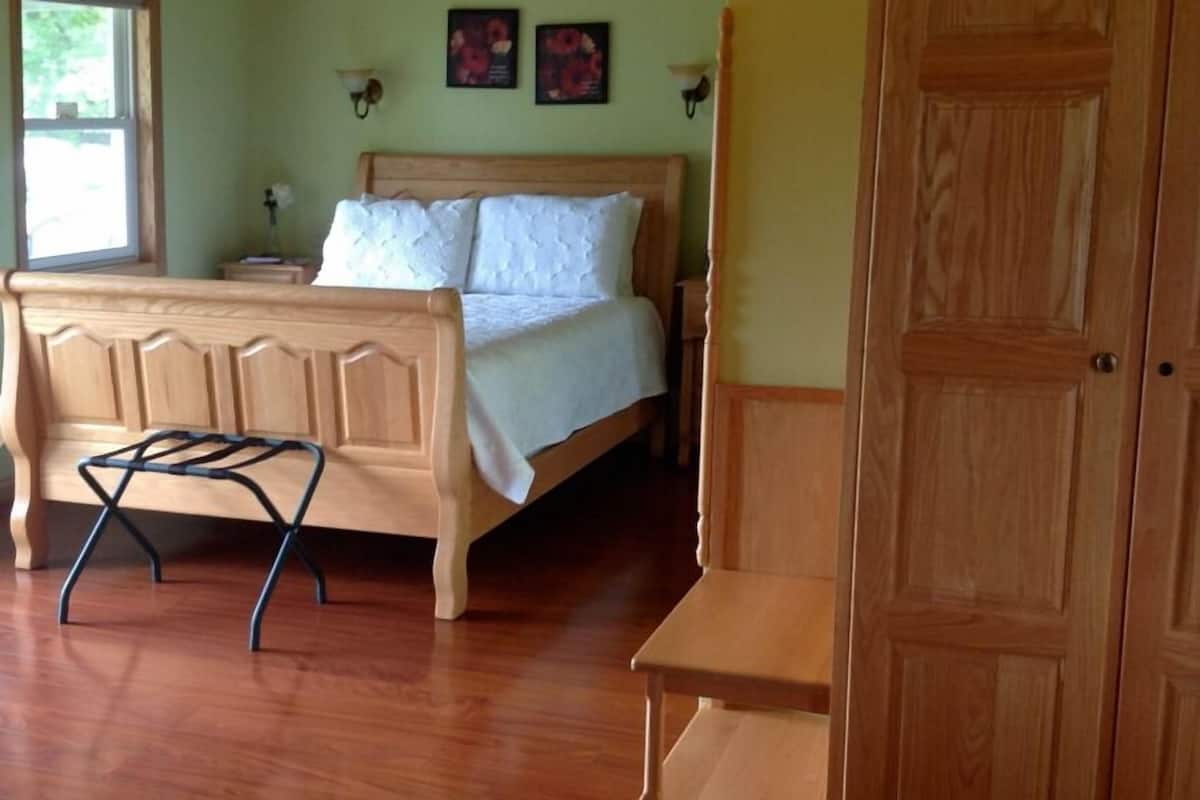 Quarto com cama de madeira, mesa de cabeceira, cadeira de madeira e guarda-roupa.