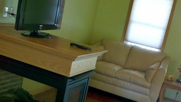 Un salon avec une table en bois, un canapé beige et un téléviseur posé sur un meuble.