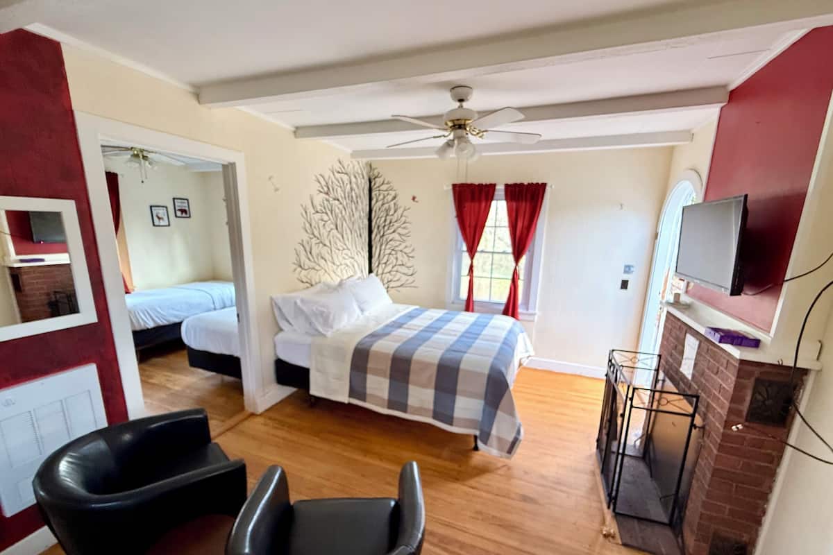 A bedroom with a bed, a chair, a television, and a fireplace.