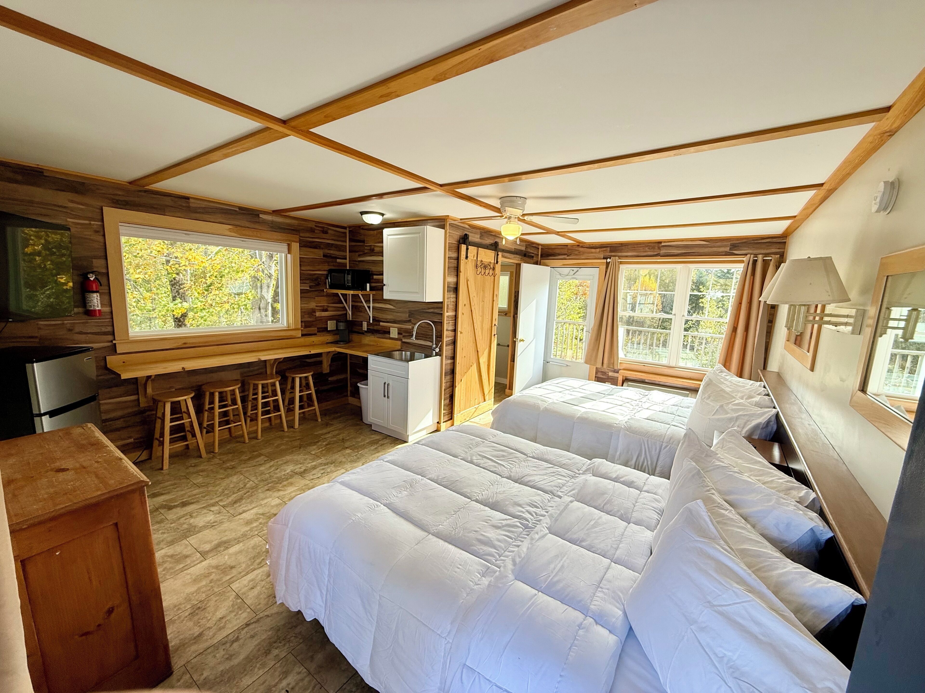 Una cabaña con dos camas, un kitchenette y un comedor con taburetes.