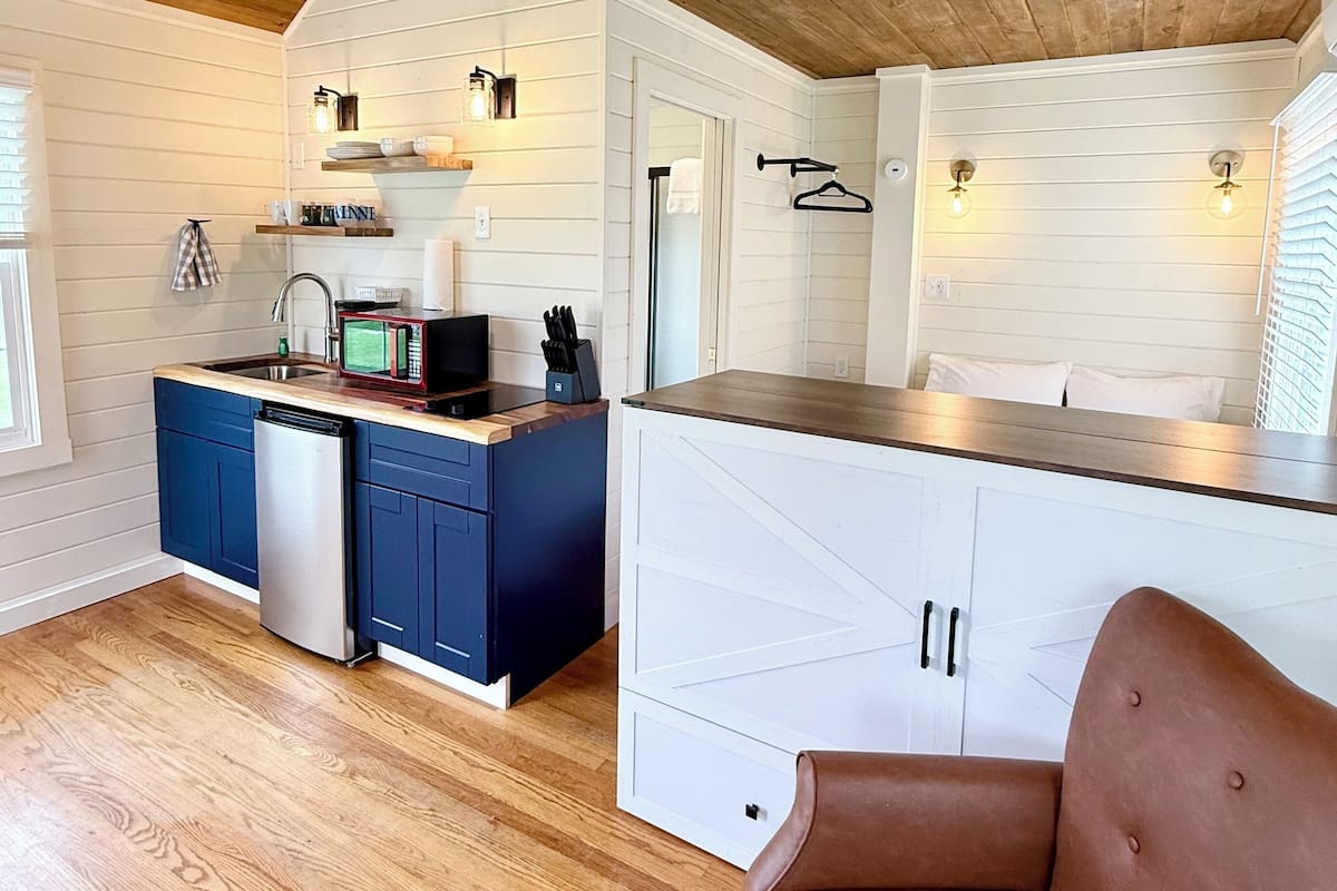 A modern kitchen with wooden ceiling, white cabinetry, and a built-in dishwasher.