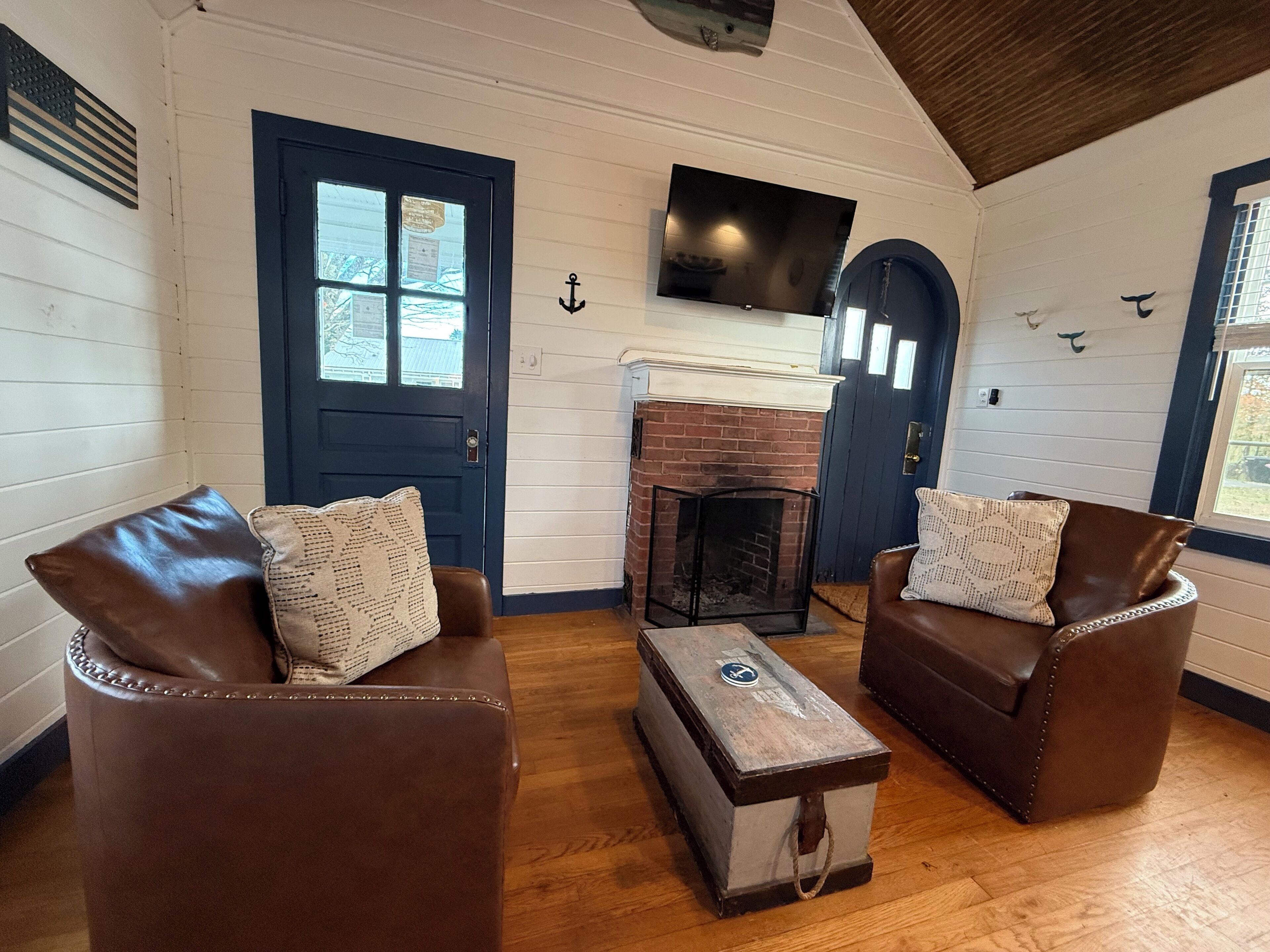 A cozy room with two leather sofas, a fireplace, and a TV mounted on the wall.