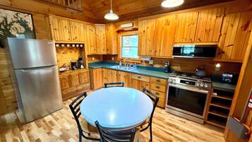 Une cuisine de style rustique, avec des éléments en bois, un îlot central, des appareils en acier inoxydable et un coin repas avec des chaises.