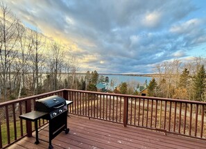 A deck with a grill, overlooking a lake and forested area. - Eden Village Motel & Cottages (Bar Harbor)