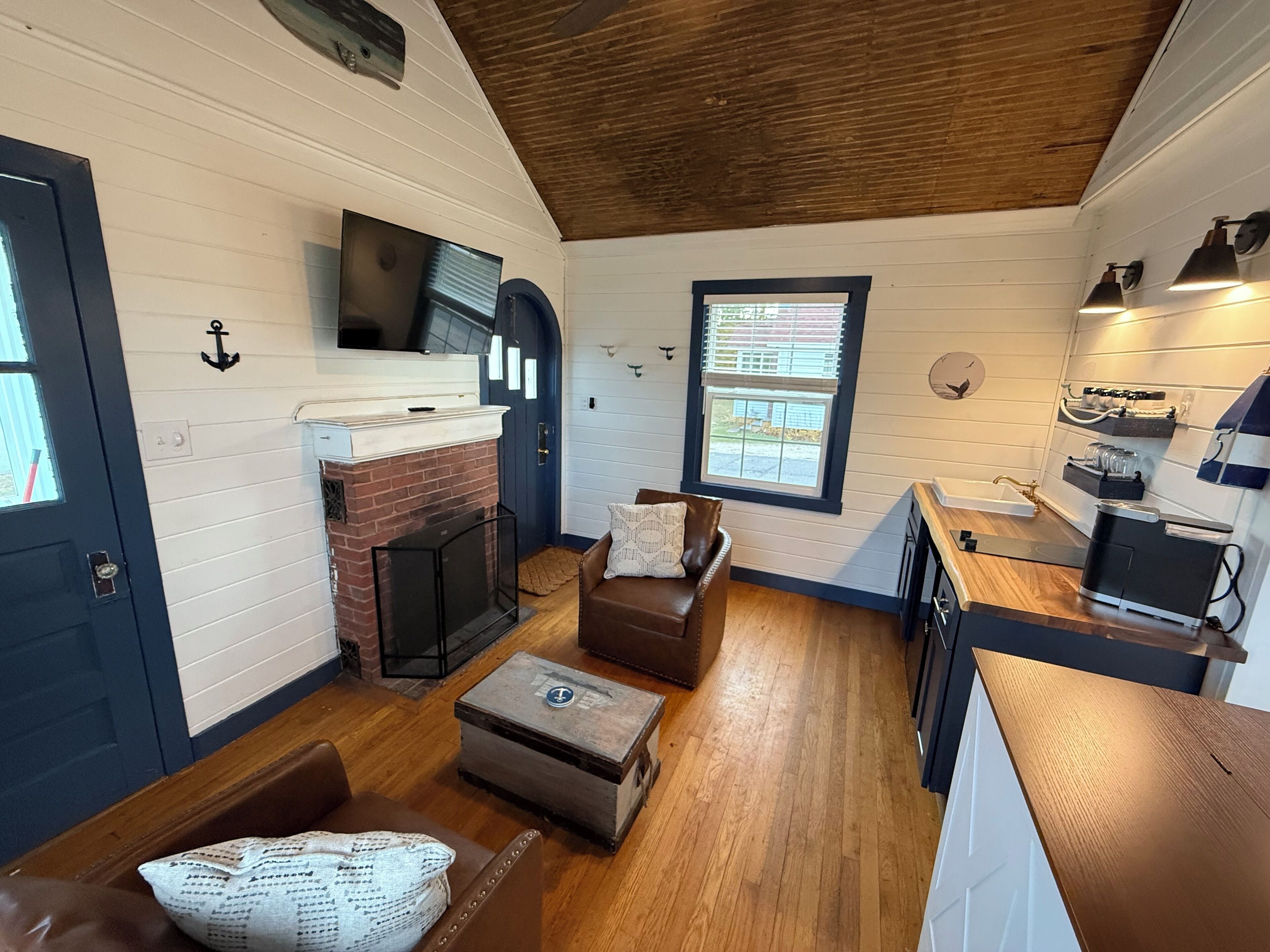 Una sala de estar acogedora con chimenea, un espacio de descanso cómodo y una cocina con electrodomésticos modernos.