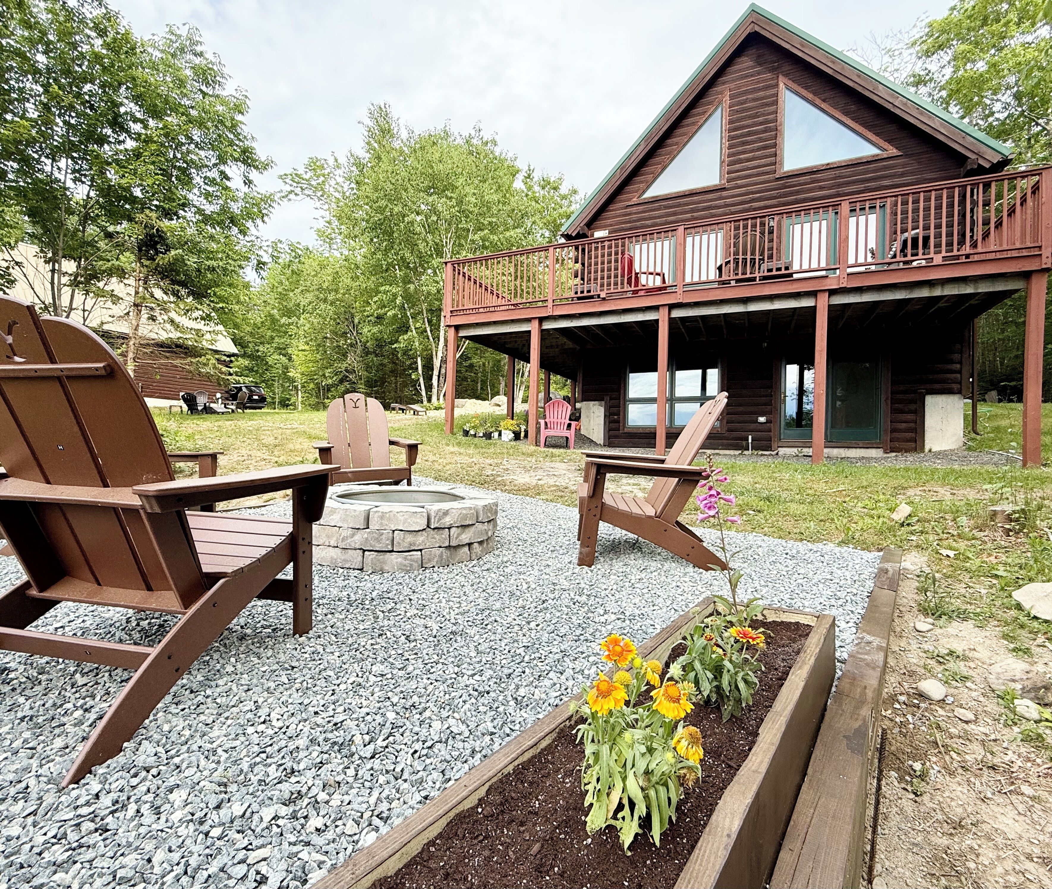 A cabin with a deck, outdoor seating, and a fire pit.
