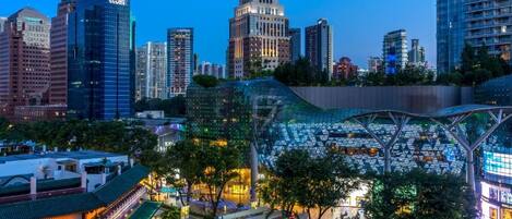 A modern cityscape with high-rise buildings, a distinctive glass structure, and a traditional building with a green roof.