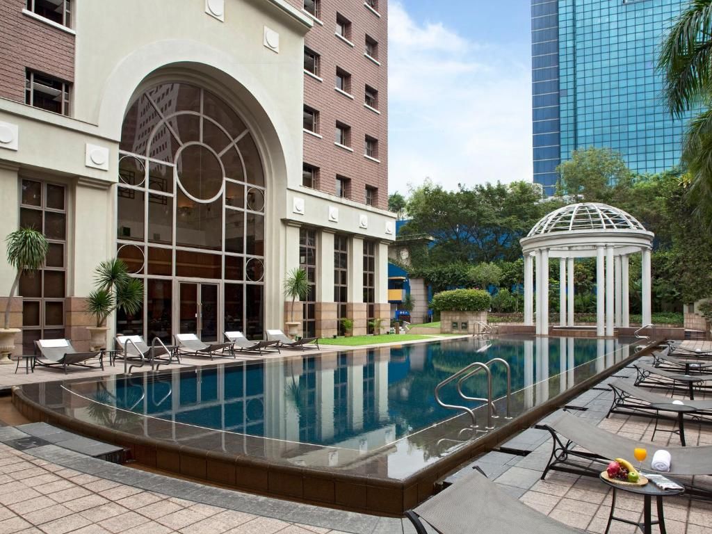 A swimming pool with lounge chairs and a gazebo in a hotel courtyard.
