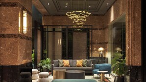 Eine moderne Lobby mit einer Couch, Hocker und einer Stehlampe.