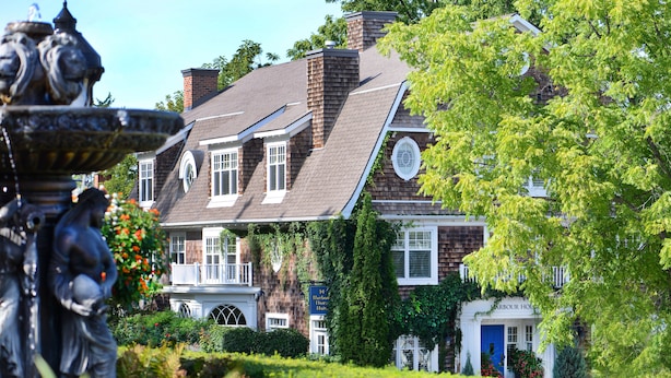 Una casa de estilo victoriano con una chimenea destacada, ventanas dormerunas y una puerta azul.