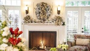 Una sala acogedora con chimenea, un sillón estampado y un adorno festivo sobre la repisa.