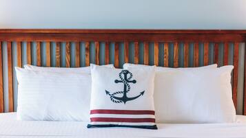 A bed with white bedding and pillows, one with a nautical anchor design.