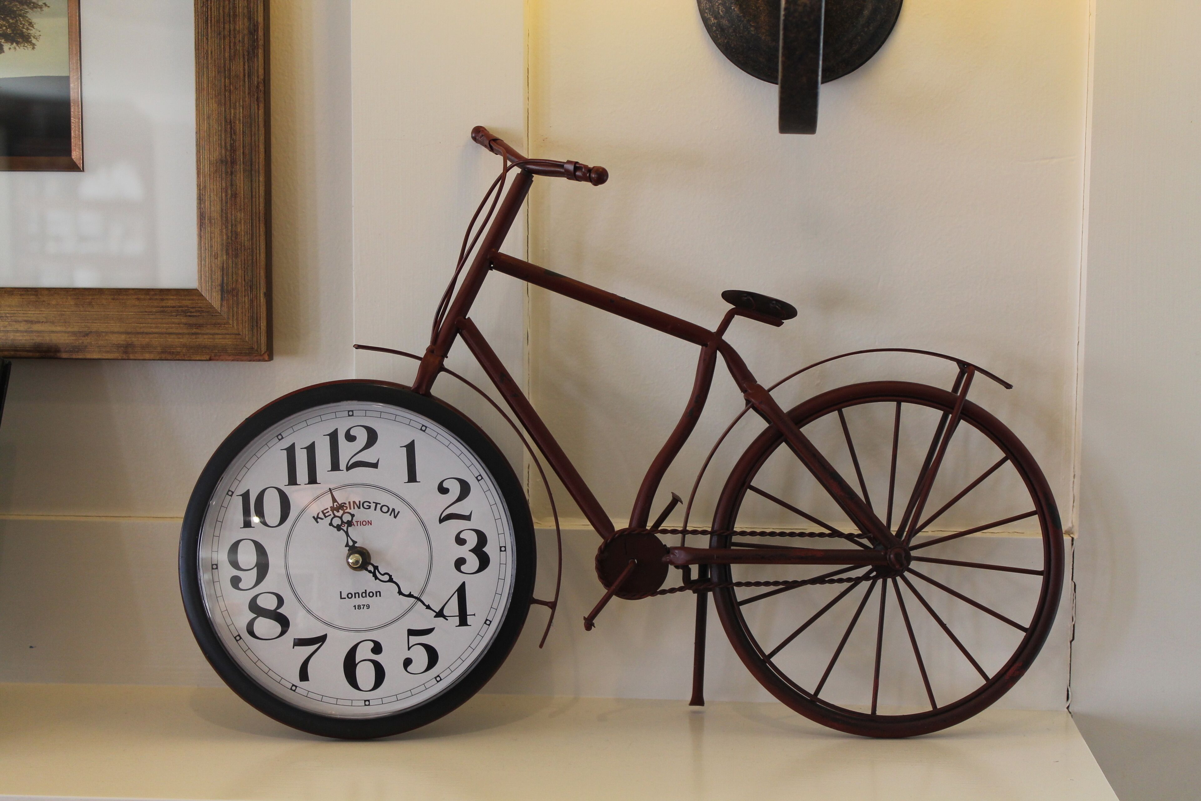 Une horloge murale dont le cadran est conçu comme une roue de vélo, un tableau encadré et un élément décoratif mural rond.