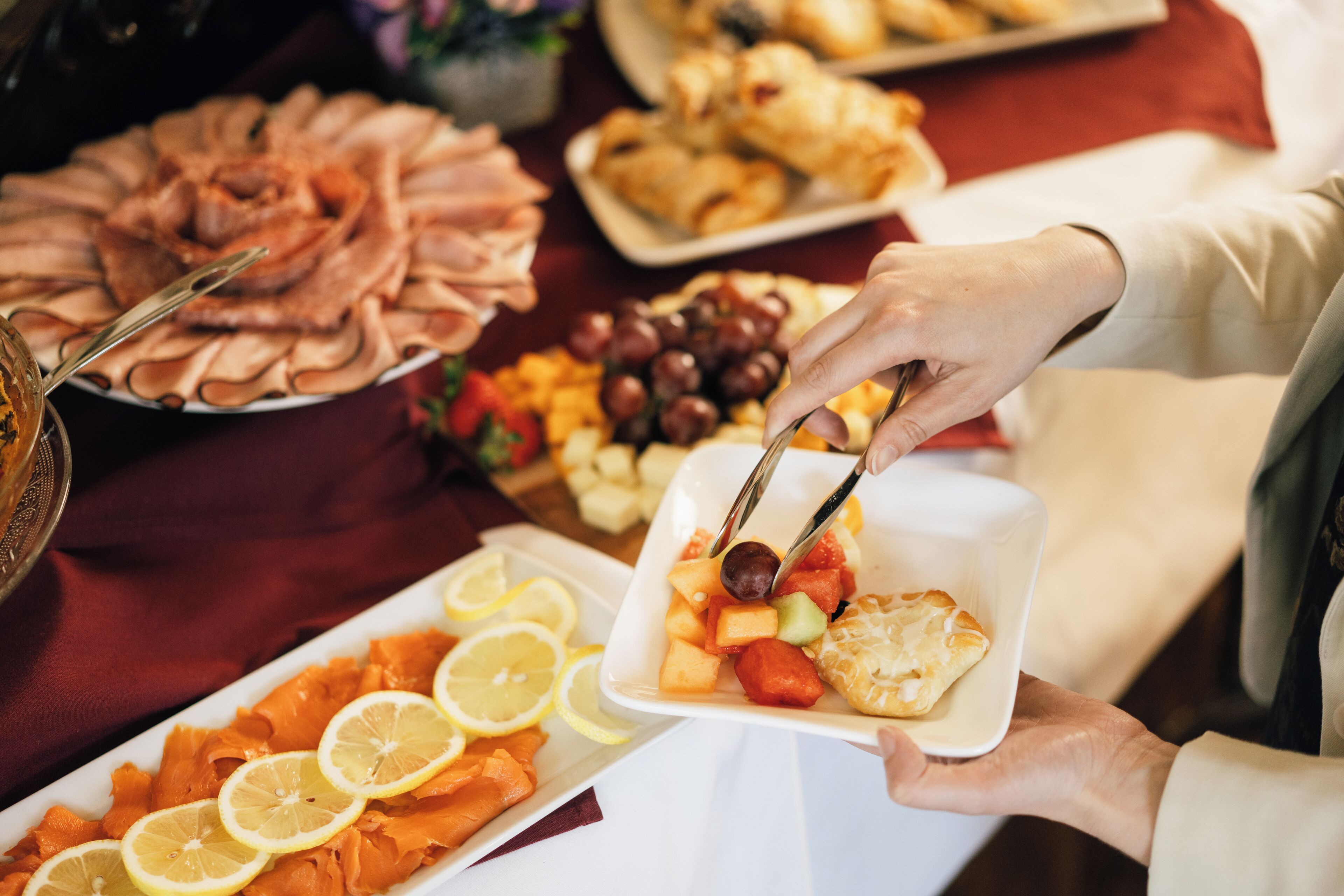 A buffet table with various food items including smoked salmon, fruits, and pastries.