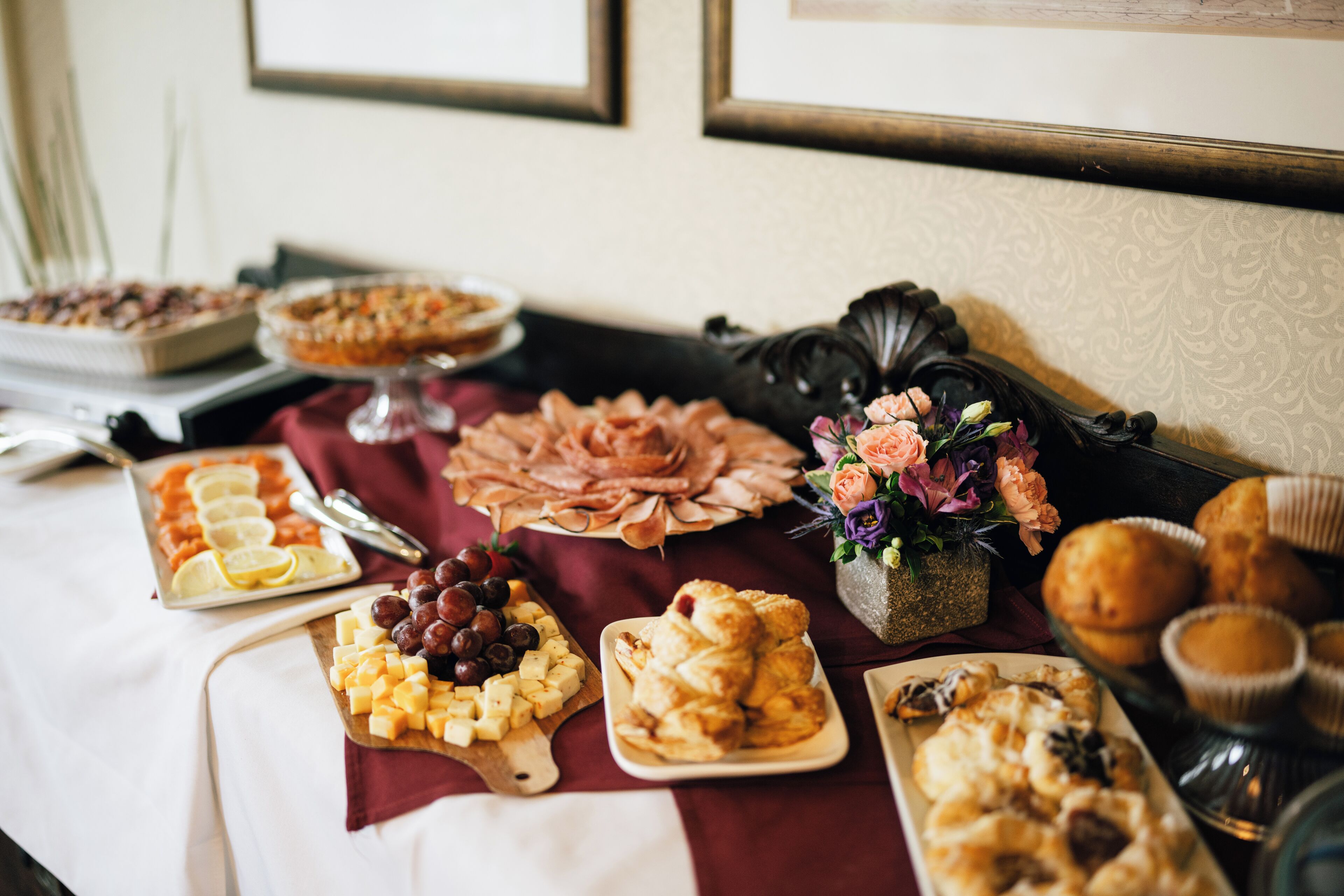 Un tavolo per buffet con diversi cibi tra cui formaggio, uva, pasticcini e pane.