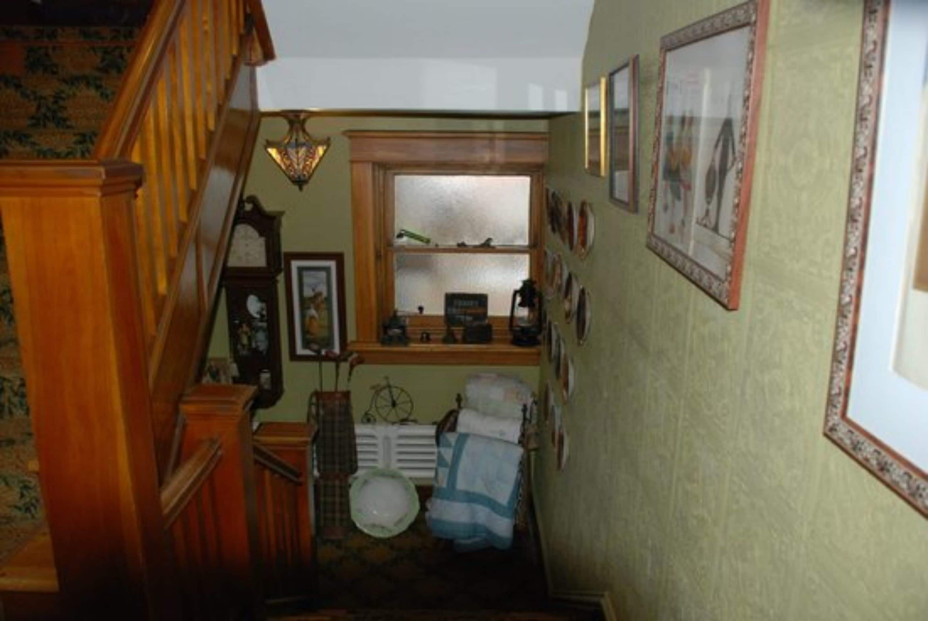 A staircase leading to a room with a radiator, a clock, and a window.