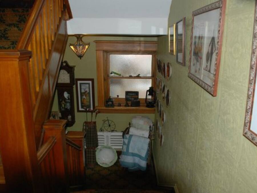 A staircase leading to a room with a radiator, a clock, and a window.