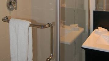 A bathroom with a glass shower enclosure, a white sink, and a towel rack.