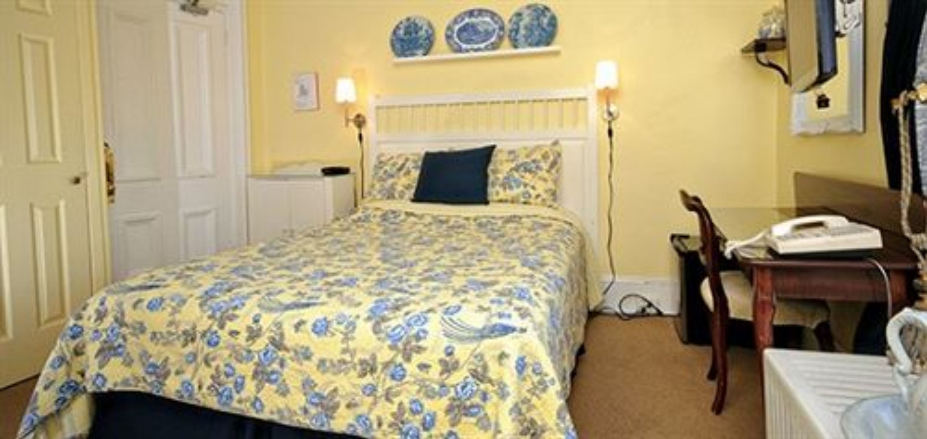 Une chambre à coucher avec un lit, une table de chevet, une chaise et un bureau.