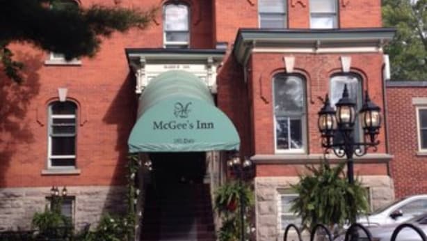 Un edificio de ladrillo con un toldo verde que dice 'McGee's Inn'.