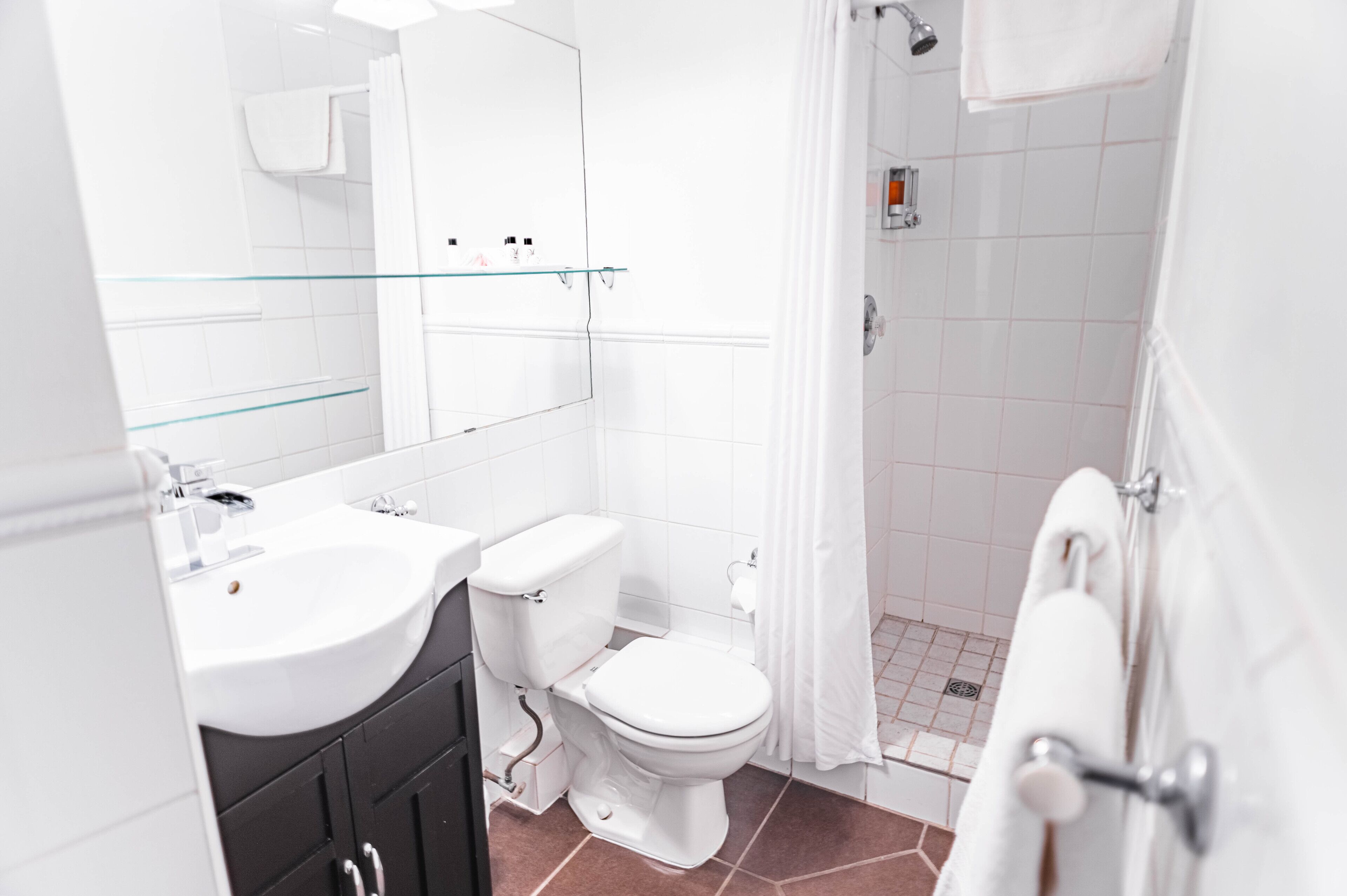 Ein modernes Badezimmer mit Waschbecken, Toilette und Dusche – alles in Weiß.