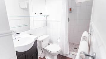 Ein modernes Badezimmer mit Waschbecken, Toilette und Dusche – alles in Weiß.
