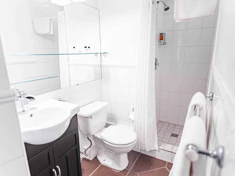 Ein modernes Badezimmer mit Waschbecken, Toilette und Dusche – alles in Weiß.
