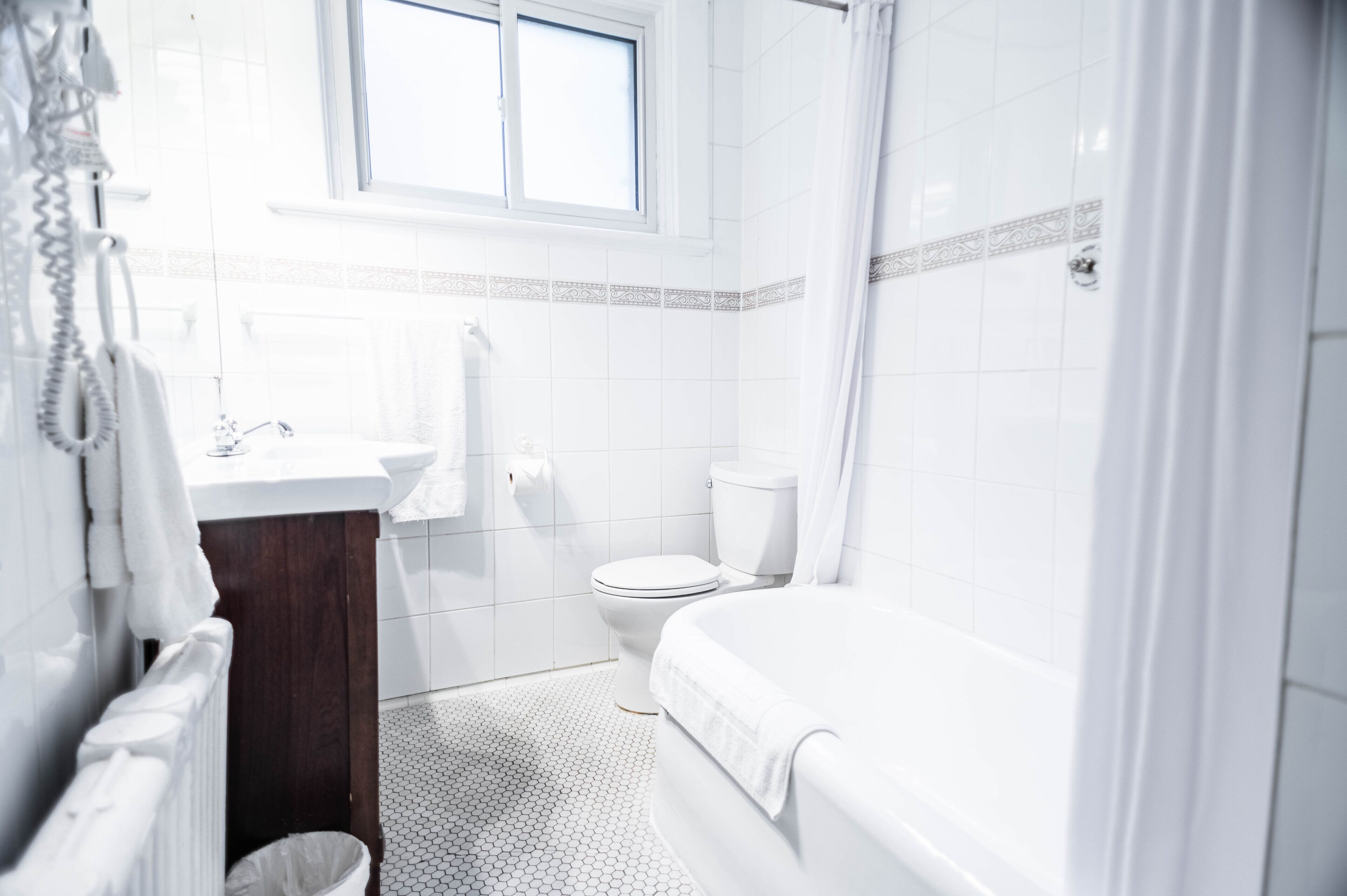 Et badeværelse med toilet, vask og badekar.