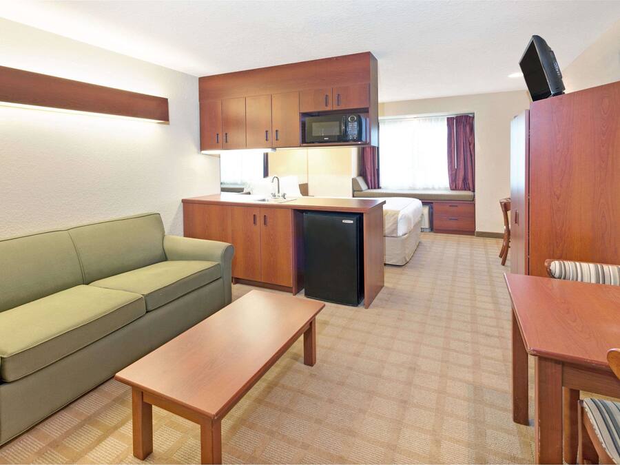 Ein gemütliches Hotelzimmer mit Küchenzeile, einer Sitzecke, einem kleinen Esstisch und einem Bett.