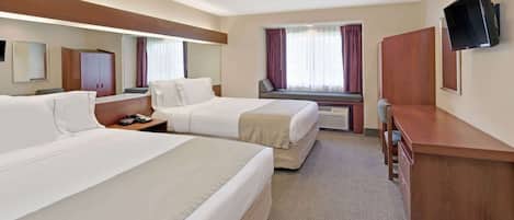 A hotel room with two beds, a desk, a chair, a TV, and a window with curtains.