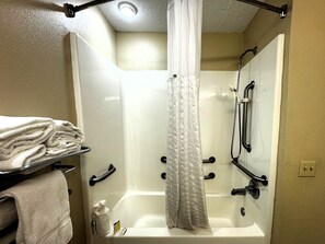 Un baño con bañera, ducha y toallero con toallas dobladas.