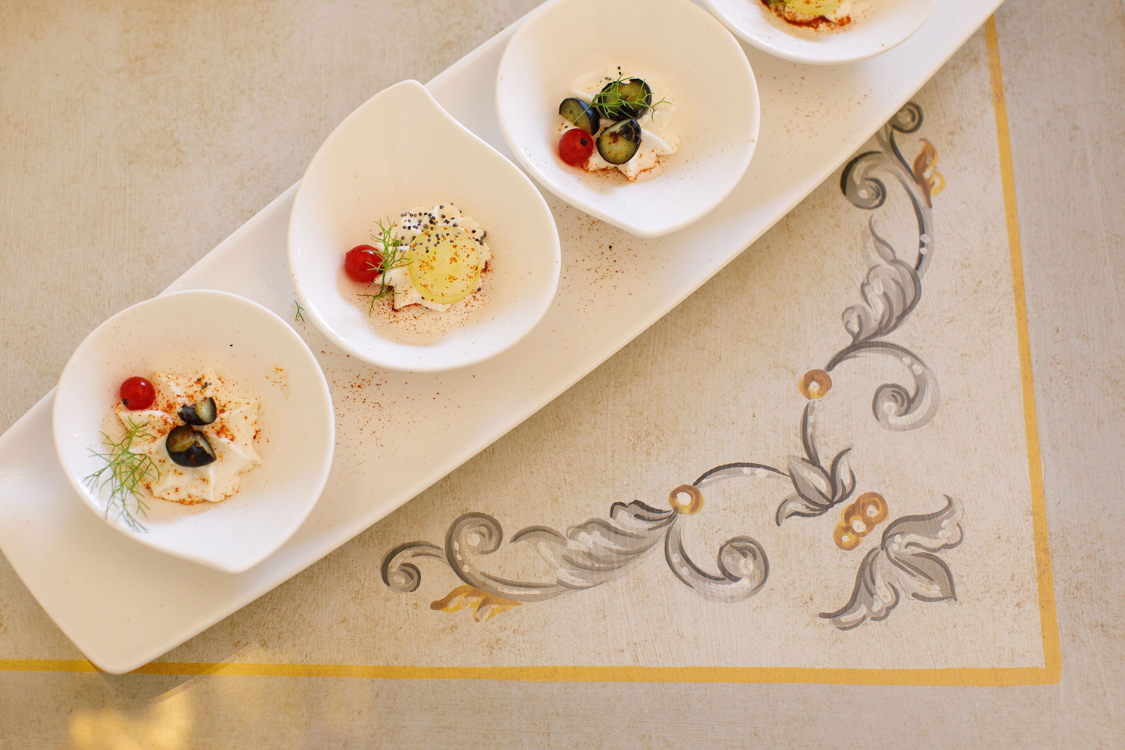 A table with three white plates containing food, each with a decorative pattern on the tablecloth.