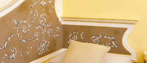 A bed with a decorative headboard, a pillow, and a nightstand.