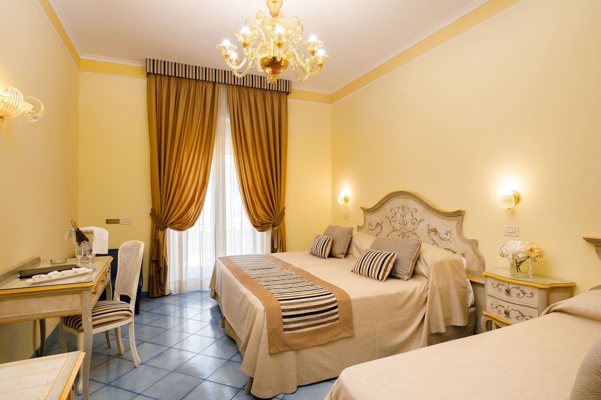 Una habitación de hotel con cama, escritorio, silla y candelabro.