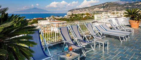 Una terraza en la azotea con sillones de descanso, mesa de billar y vistas al mar y a las montañas.