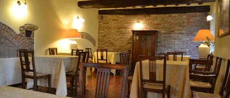 A dining area with wooden tables and chairs, brick walls, and exposed wooden beams.