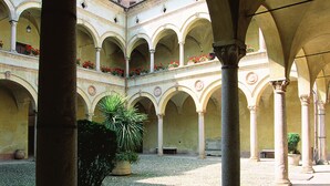 An open courtyard with arches, columns, and potted plants. - Hotel Residenza Torre di San Martino (Gazzola)