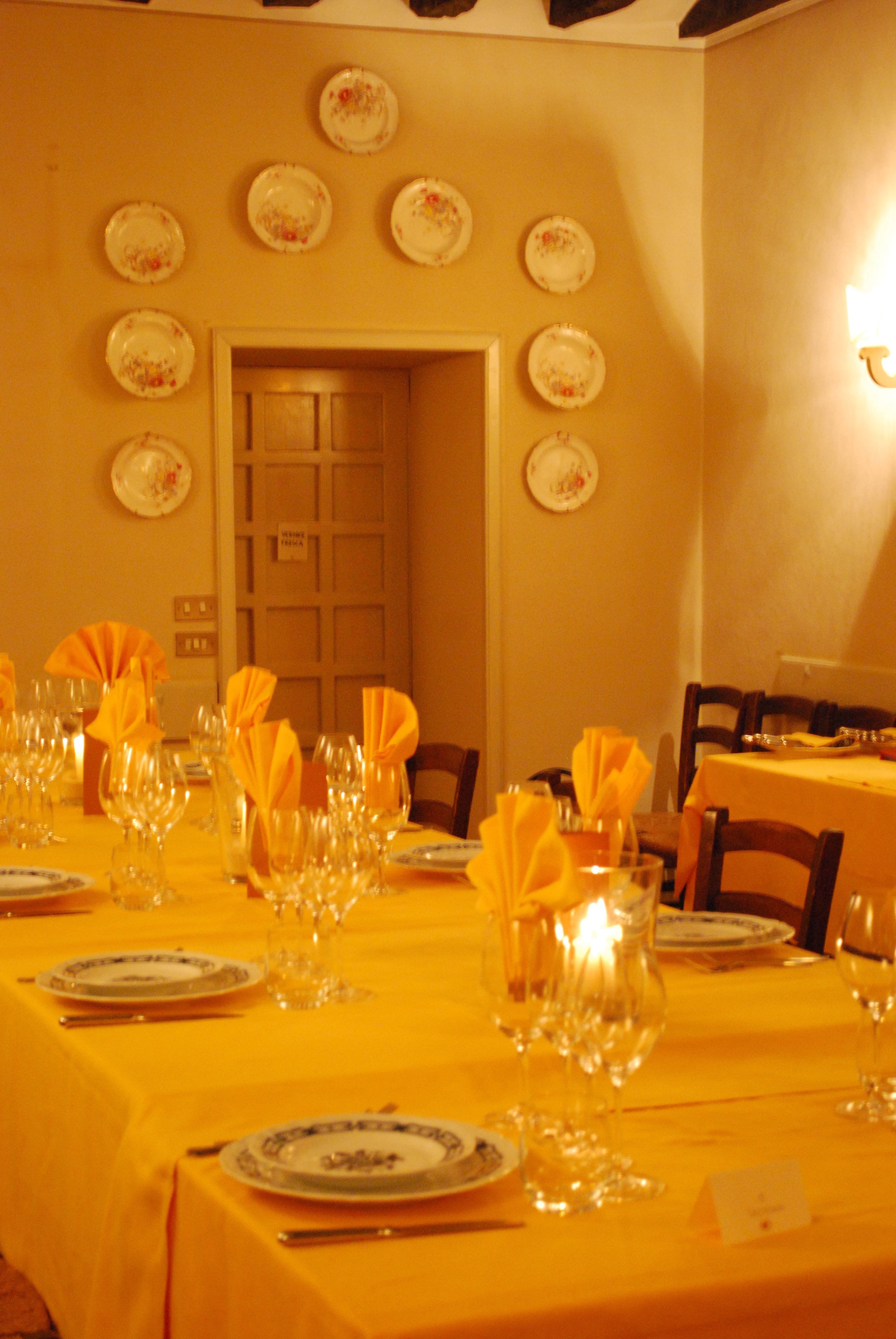 Comedor con mesas dispuestas para varios comensales, con manteles amarillos y cristalería y platos ordenados.