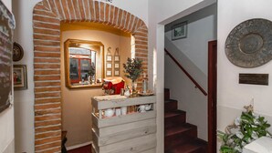 Eine Holzhandrail und ein Ziegelbogen führen zu einem Raum mit einem Spiegel und gerahmten Bildern.