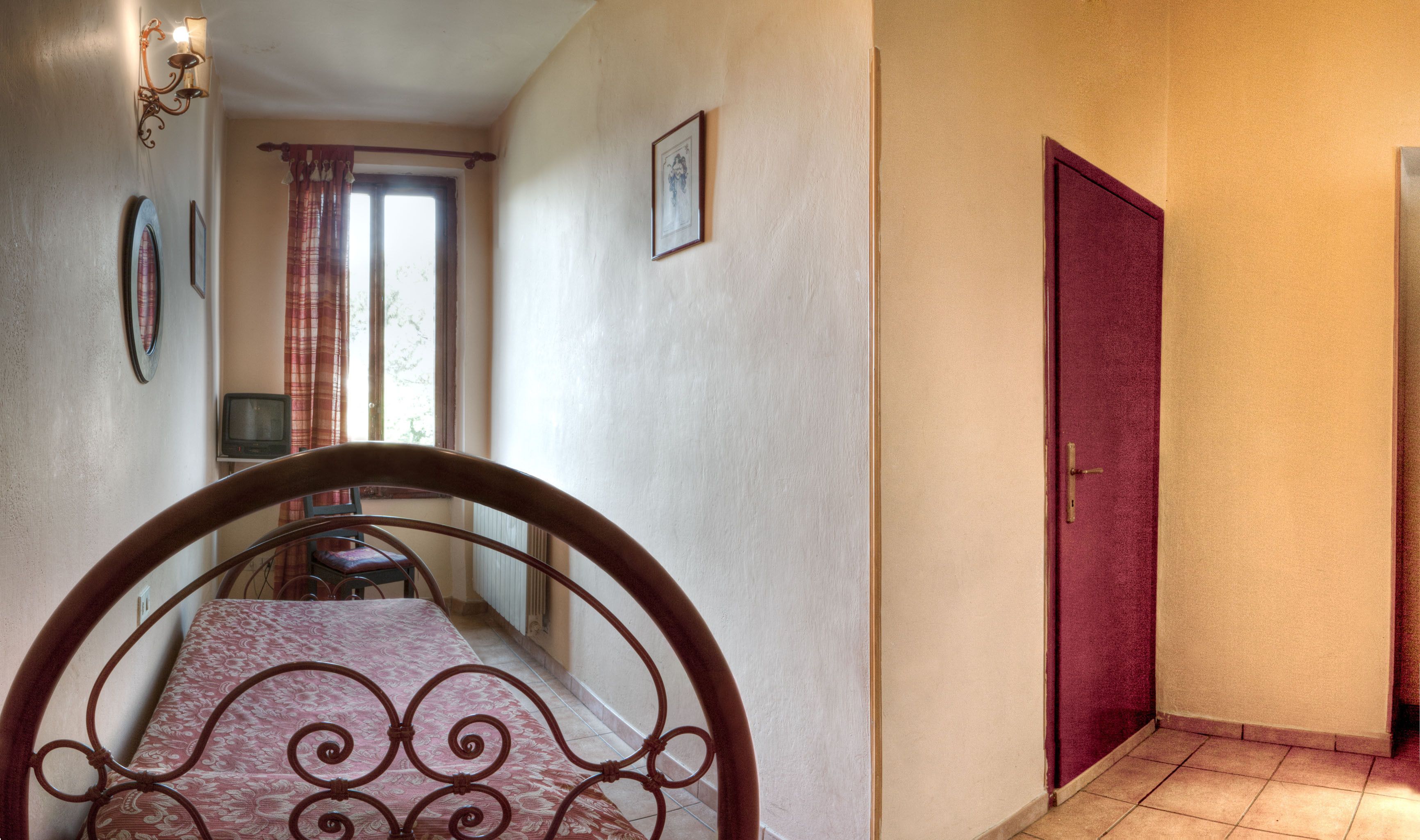 A hallway with a wooden chair, a red door, and a window with curtains.