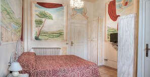A bedroom with a bed, a radiator, a television, and a mural on the wall. - Hotel Masaccio Florence (Florence)