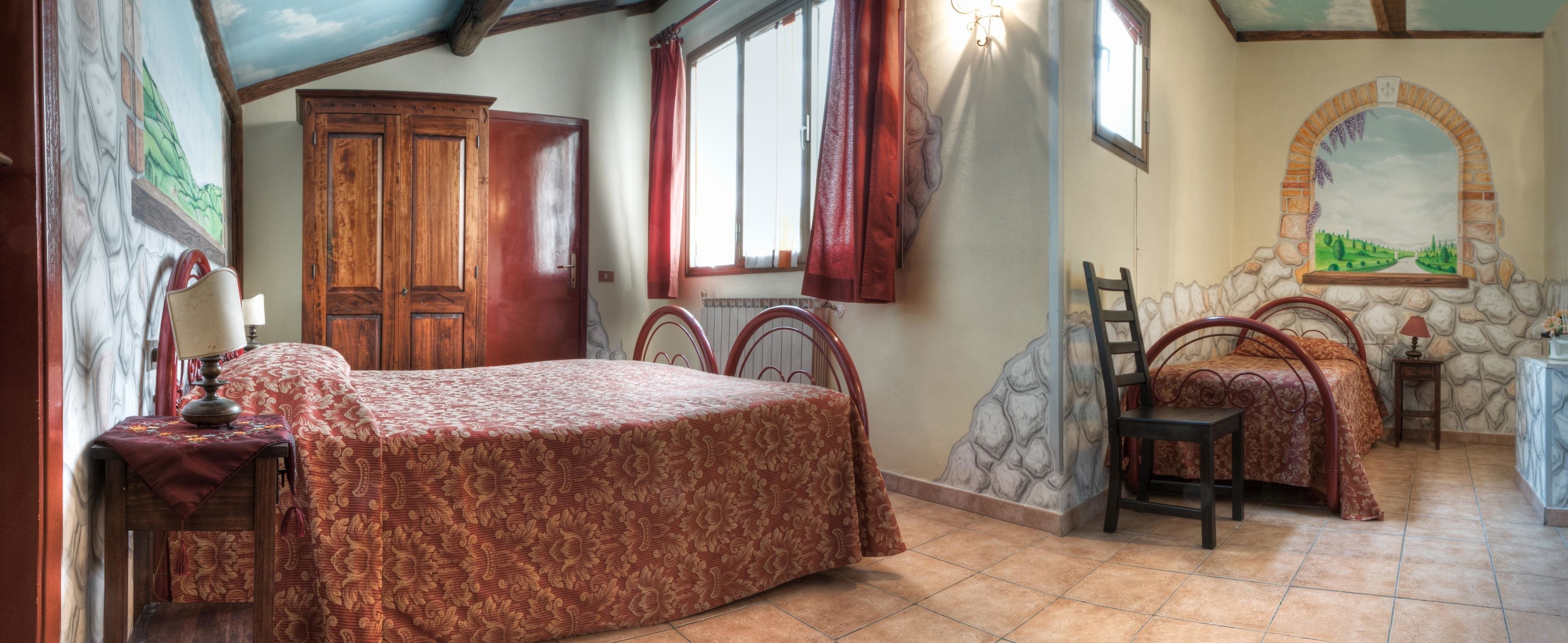 Un dormitorio con cama, dos sillas, un armario de madera y una pared de piedra con un mural.