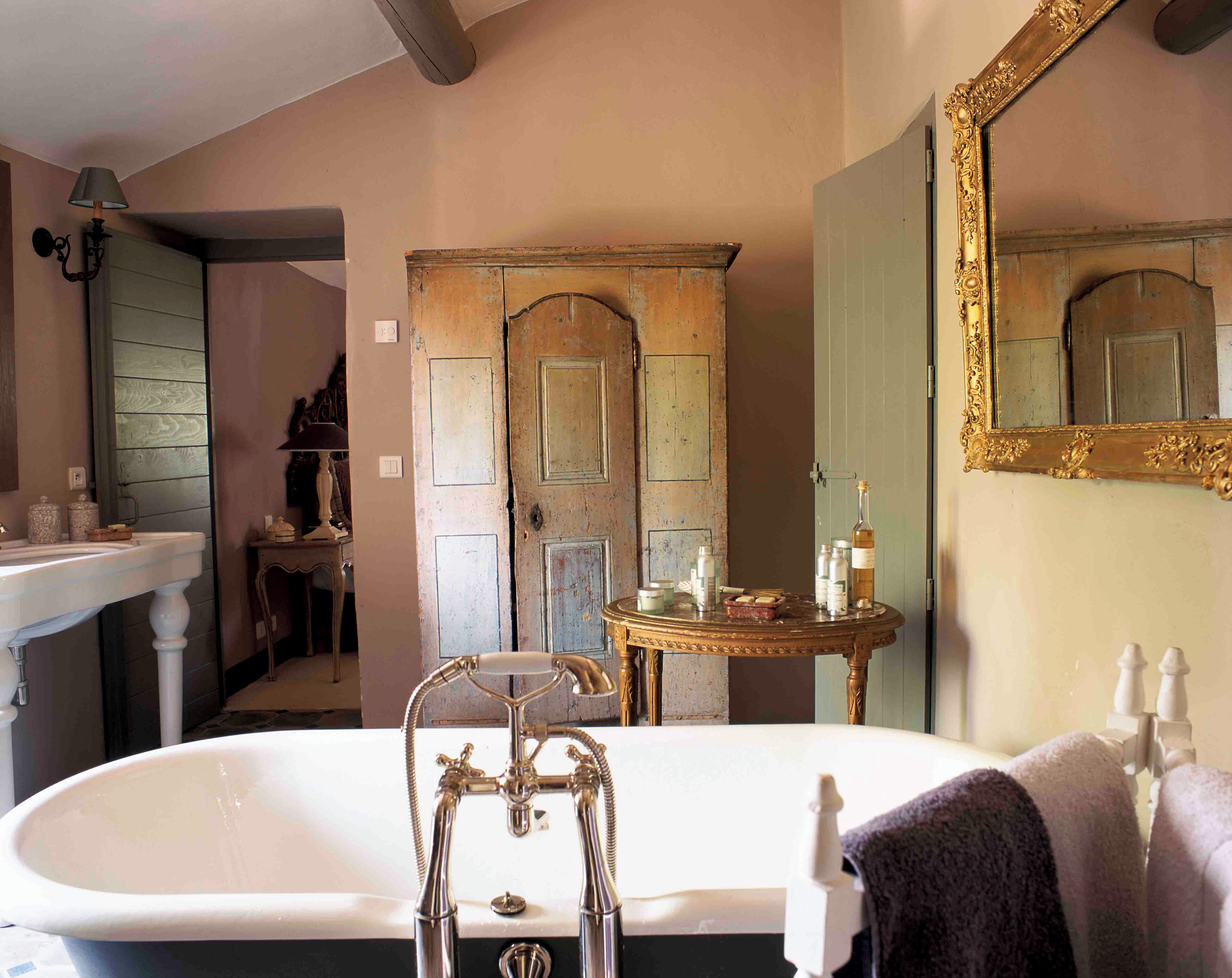 A bathroom with a freestanding bathtub, a sink, a vanity, and a mirror with an ornate frame.