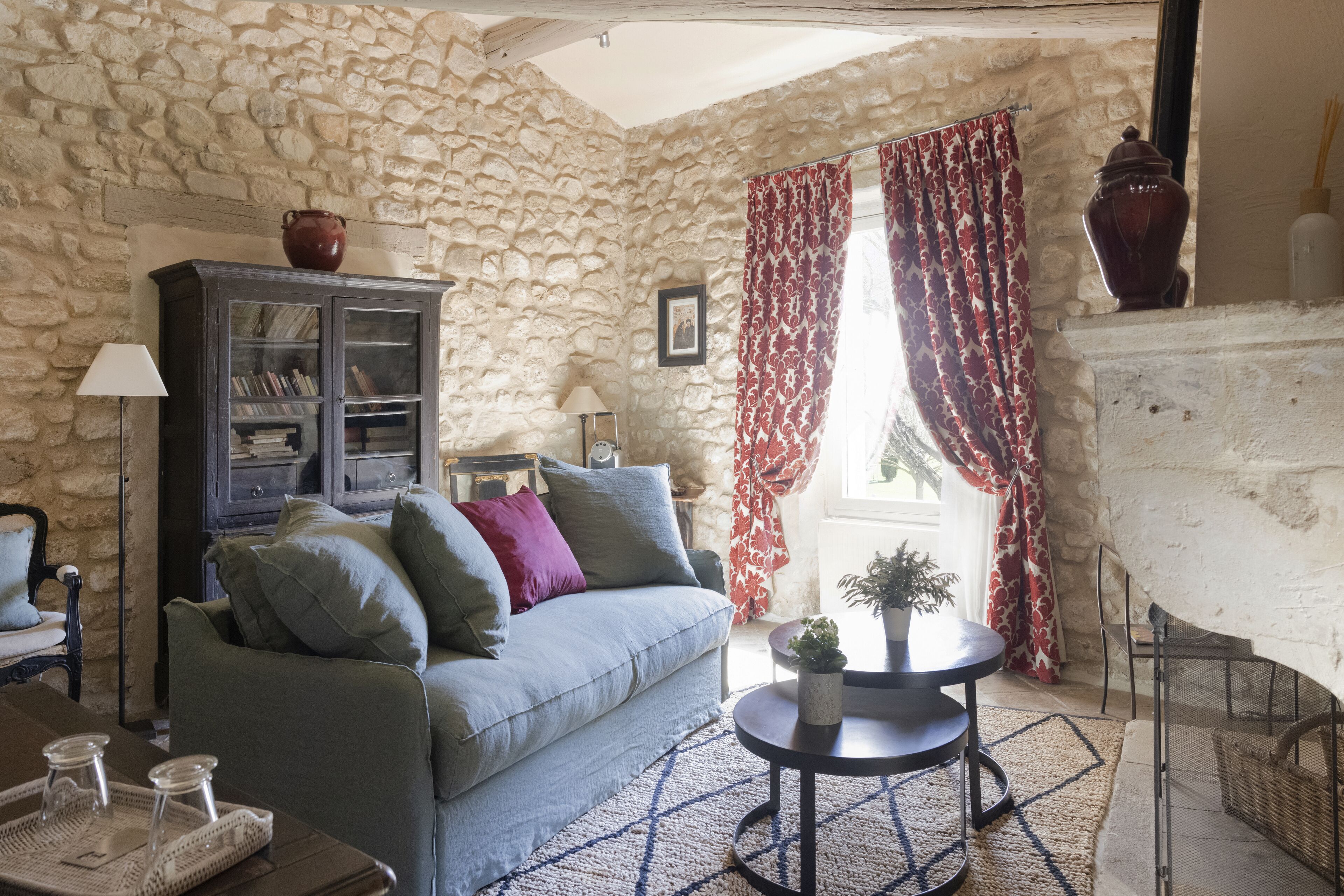 Una sala de estar acogedora con una pared de piedra, un sofá con cojines, una mesita con una planta y una chimenea.